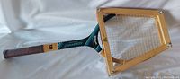 Side view of Wilson Chris Evert Champion Edition wooden tennis racquet with Jelinek wooden brace, showing loose strings and minor dent on racquet head.