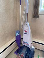 Photo showing Bissell Quick Steamer Plus and Wet Jet Swiffer together in a corner