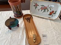 Clay wine cooler with fruit design, miniature bowling game, pottery dish on stand, and Royal Worcester serving dish on white cloth.