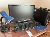 Photo showing emachines EL1352 monitor, keyboard, blue desk lamp, and computer tower on wooden table.
