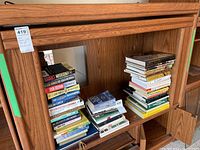 Front view showing MDF entertainment cabinet with two large stacks of assorted books inside its main compartment.