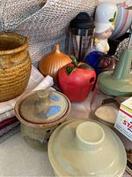 Image showing multiple ceramic kitchen items including lidded canisters, a pitcher, apple-shaped accessory, and coffee cup.