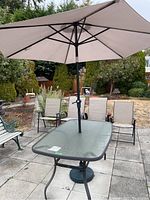 Full view of outdoor patio table with umbrella and chairs on stone patio outdoors in garden setting.