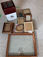 Photo of assorted picture frames arranged on carpet with photo box visible