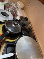 Metal pots and pans with lids, a mesh splatter guard, and rectangular pan