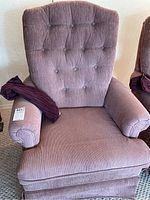 Front view of a mauve cloth swivel armchair showing button-tufted backrest and rolled armrests with a cushion on the seat.