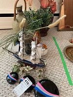 Three black vases with decorative felt bands, faux flowers, and small sailboat model