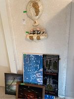 View of ceramic wall decoration and wall planter with faux flowers mounted on wall, plus multiple framed art pieces below