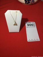 Gold chain necklace displayed on jewelry bust with bicycle pendant visible