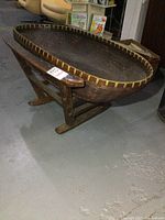 Side angle of large oval woven basket sitting inside wooden frame on floor