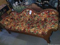View of the antique settee showing full length with floral upholstery and wooden frame.