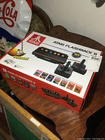 Atari Flashback 8 box showing console and 2 controllers on top of a wooden table.