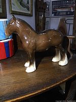 Side profile of brown Beswick horse figurine showing glossy finish, feathered legs, and overall shape.
