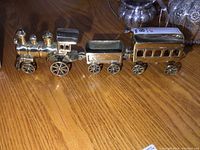 Full view of the three-piece brass train set on a wooden surface.