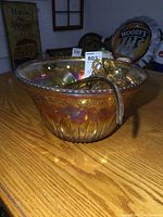 Front angled view of the amber iridescent carnival glass punch bowl with ladle resting inside
