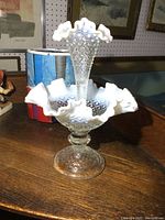Front view of the opalescent hobnail glass 2-piece epergne centerpiece showing the top trumpet-shaped vase with ruffled edge.