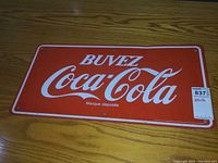 Full view of the red and white Coca-Cola metal sign with 'BUVEZ' text and 'Marque déposée' printed underneath.