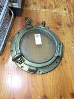 Front view of entire round brass porthole showing mounting flange and glass surface