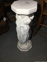 Full side view of the white plaster plant stand showing the nude female figure and hexagonal top and base.