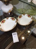 Pair of oval veggie dishes in Royal Albert Old Country Roses pattern with floral design and gold trim, displayed on glass shelf.