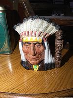 Front view showing Native American Indian face, feather headdress, and totem pole handle.