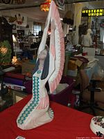 Oblique side view showing statue's detailed painted wings and clothing patterns on crushed marble surface.