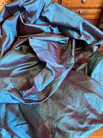 Photo showing the iridescent silk fabric loosely gathered to highlight color shifting between deep blue and burgundy tones.