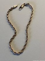 Full view of the gold rope link bracelet laid out with clasp closed.