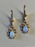 Front view of both earrings showing scroll design and opal stones