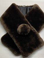 Full view of the folded dark brown mink fur scarf/collar with visible fur-covered button closure and smooth black lining on the reverse.