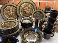Full set displayed on countertop showing plates, bowls, cups, saucers and serving pieces.