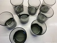 Overhead view showing all 8 smoky grey lowball glasses arranged together, showcasing their translucent color and uniform size.