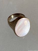Photo of a sterling silver ring with an oval mother of pearl stone set in the band showing front and side angles.