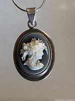 Front view of oval sterling silver cameo pendant showing detailed female profile on blue background with accompanying silver chain