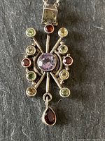 Close-up of entire pendant showing the symmetrical design and multi-colored stones.