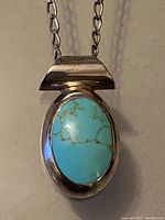 Front view of the vintage sterling silver pendant with turquoise stone on chain, showing the oval shape and large tubular bail.