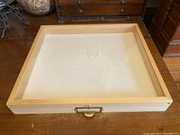 Full view of wooden display case with glass top on wooden surface.