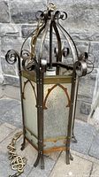 Full view of antique Gothic cathedral light fixture showing hexagonal shape, decorative scrollwork top, and textured glass panels with brass pointed arch details.