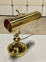 Side view showing the cylindrical brass lamp shade with vent cutouts and curved adjustable arm.