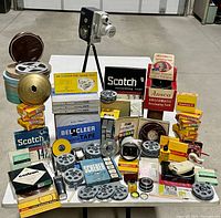 Overview of large vintage camera lot with multiple reels, tapes, camera, tripod and accessories
