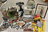 Full lot view showing Philips radio, Oster hair dryer, postcards, silverware, tools, and small collectible items