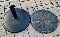 Wrought iron umbrella base beside the heavy rubber sub base showing detail of each.