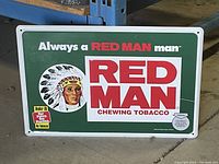 Front view of the Red Man chewing tobacco advertising tin sign showing full colorful design and warnings.