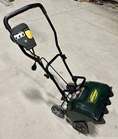 Side angled view of Yardworks snow thrower showing control panel, handle, wheels, and snow chute.
