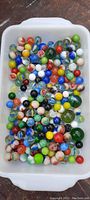 Photo showing a large assortment of glass marbles in a tray, diverse in color, size, and pattern.