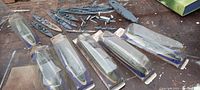 Photo showing eight ship hull model kits, mostly in cardboard backing with plastic covers, arranged on a surface with several loose metal ship parts behind them.