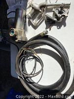 Fuel pump, hose, nozzle, mounting hardware and electrical cable arranged on a white surface showing all included physical parts.