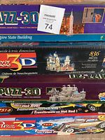 Photo of four 3D puzzles stacked: Empire State Building, Neuschwanstein Castle, Camelot, Hot Rod Roadster, with puzzle piece counts visible