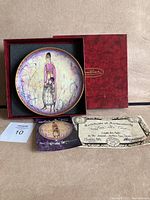 View of the plate displayed in its red presentation box with original certificate and documentation included