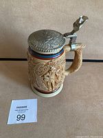 Ceramic beer stein with hinged metal lid, embossed with country and western music themed decorations and colorful top border.